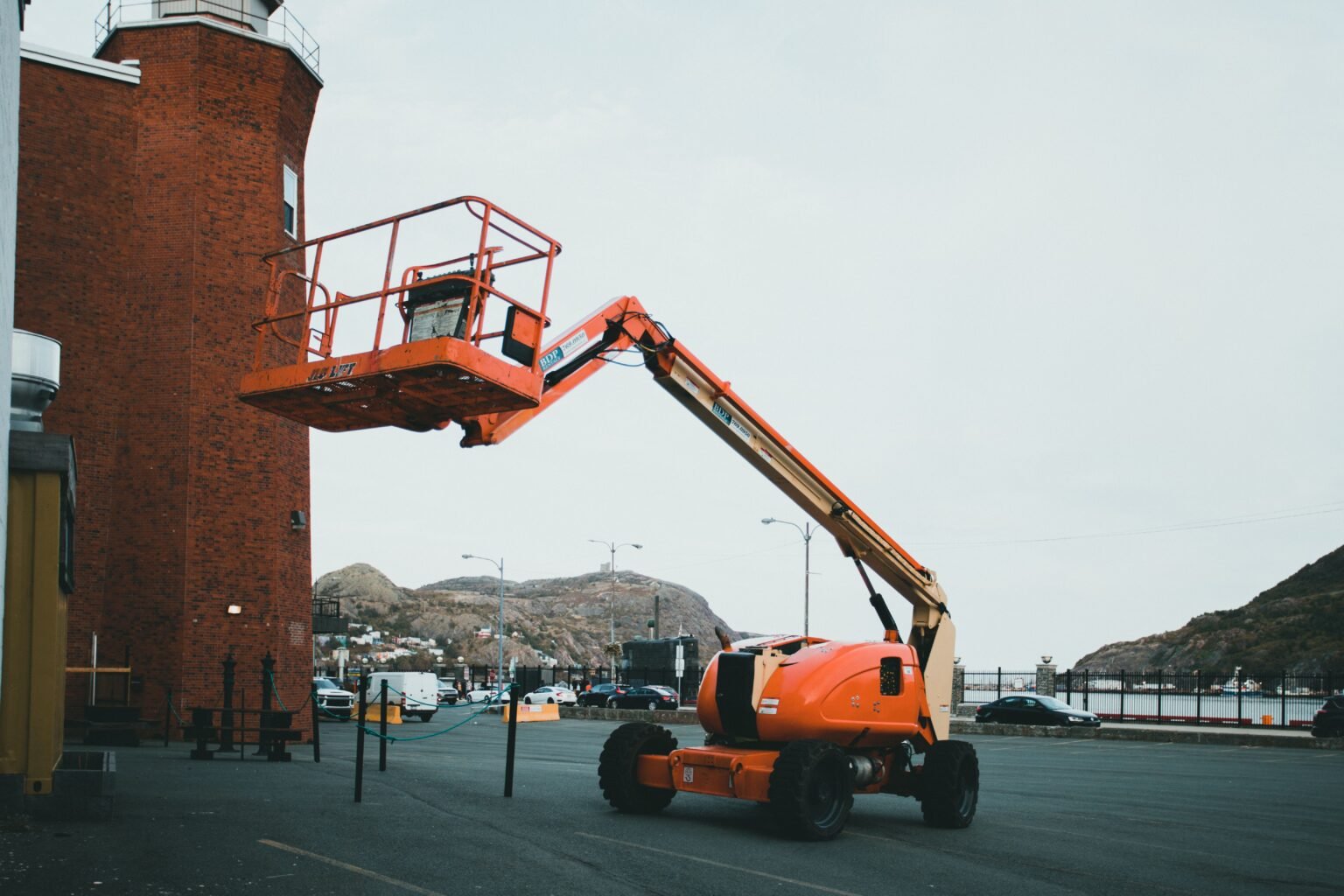 Orange boom lift (MEWP) parked outdoors ready for pre-use inspection