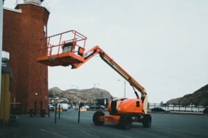 Orange boom lift (MEWP) parked outdoors ready for pre-use inspection