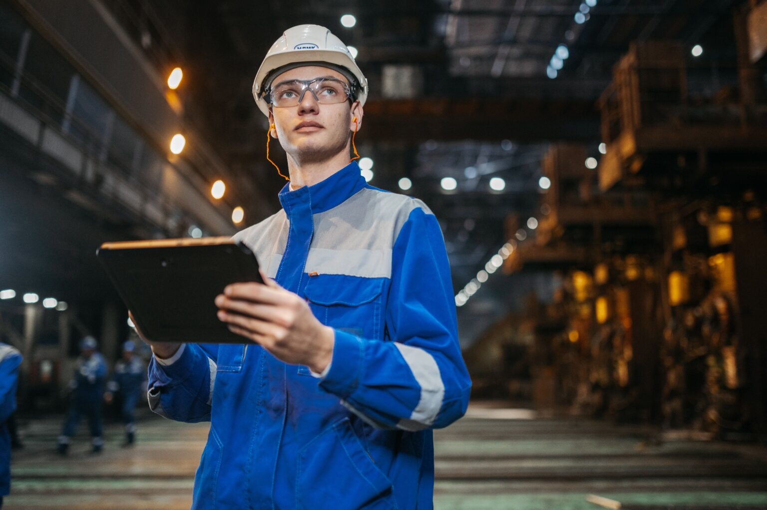 Benefits of electronic permit to work: engineer in safety gear approving a permit on a tablet at an industrial site