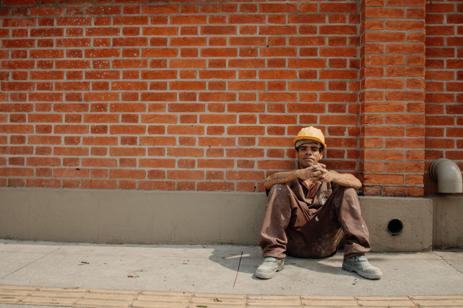 Heat Stress Management at Construction Sites – PEER Heat stress management at construction sites: tired construction worker resting against a wall in the sun
